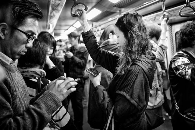 mensen bekijken hun sociale media voor updates in de trein tijdens de spits