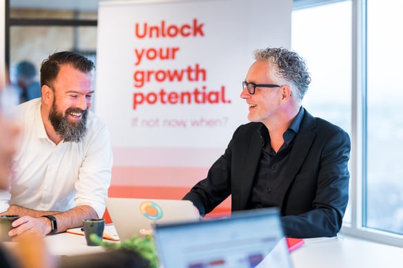 two colleagues laughing over something that is displayed on a laptop