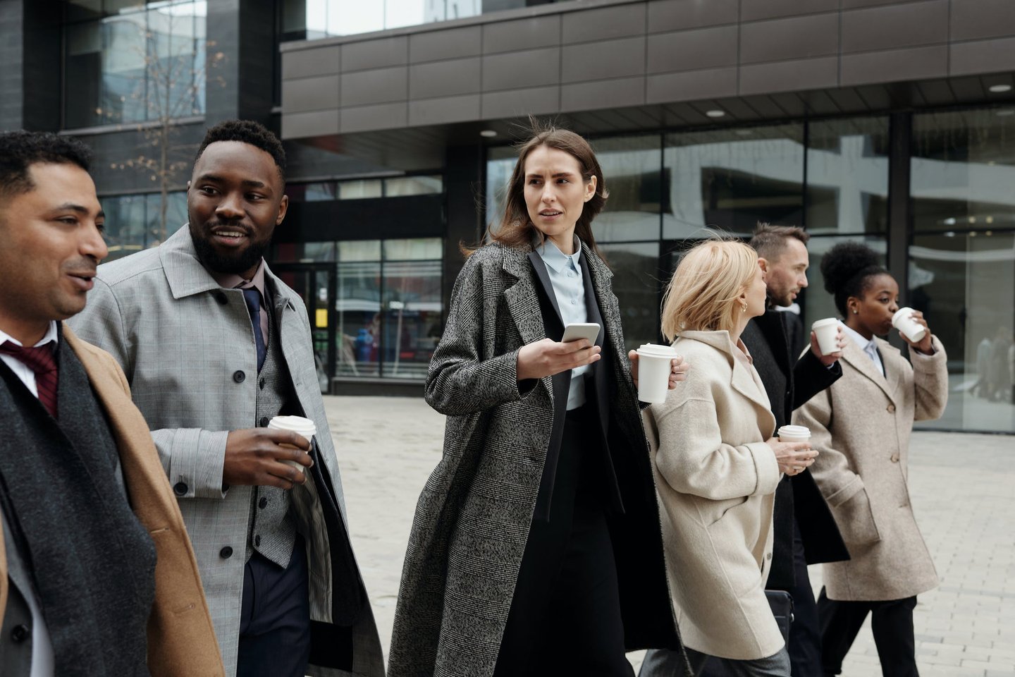 Business people walking outside drinking coffee and chatting
