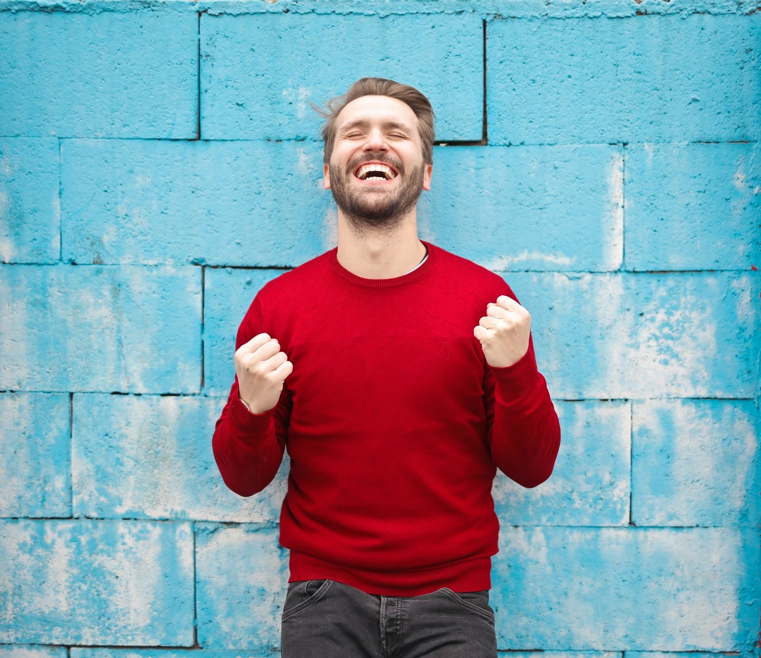 Man celebrating a victory in front of a blue wall