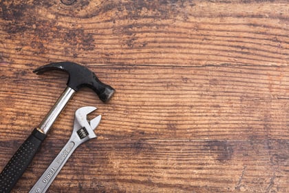 A hammer and a wrench on a woorden board