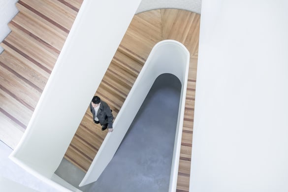 A man who is walking down wooden modern stairs