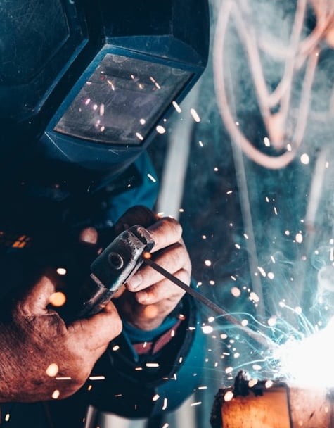 a manufacturing worker wearing a welding mask while welding